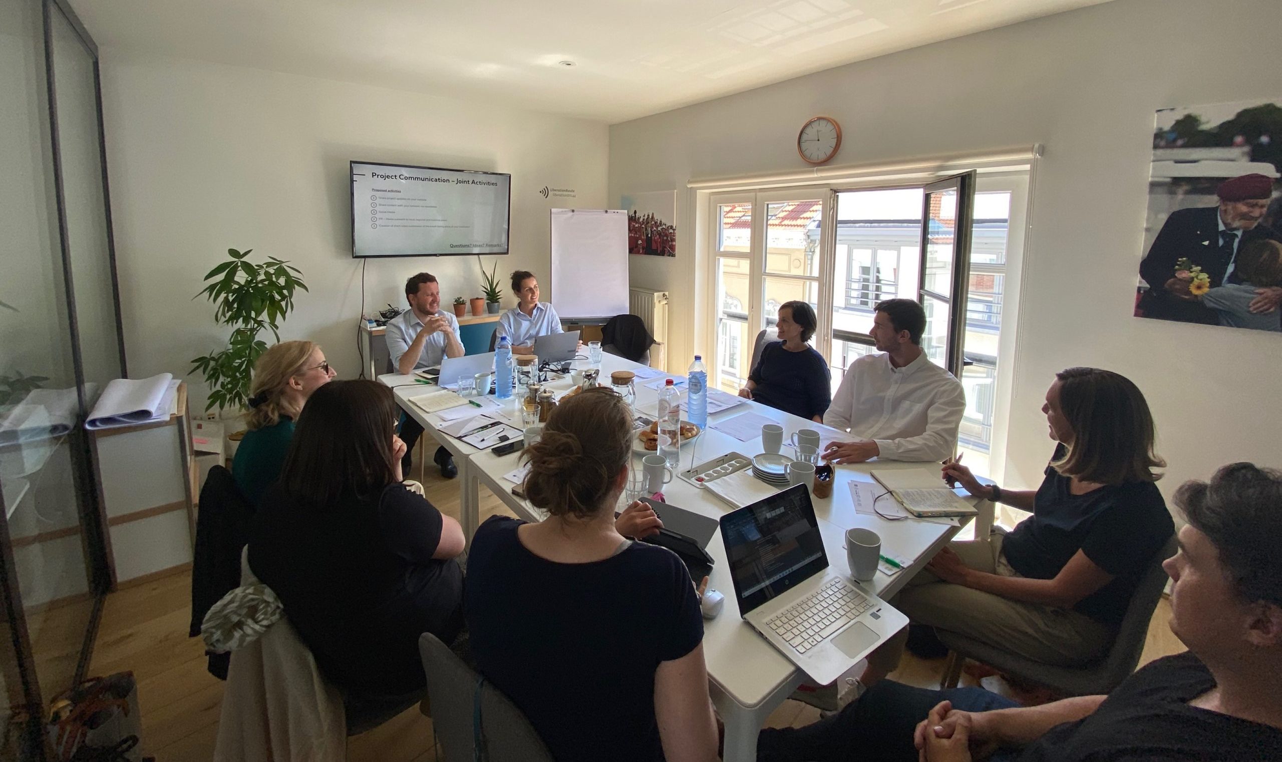 Picture of a meeting room with nine people around a table